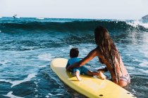 Madre e hijo surfeando una pequeña ola en el mar - foto de stock