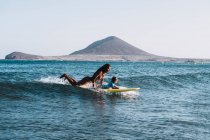 Madre e figlio facendo surf su una piccola onda in mare — Foto stock