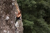 Молода жінка піднімається на скелю — стокове фото