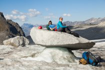 Pareja sentada en roca, Glaciar Snowbird, Montañas Talkeetna, Alaska - foto de stock