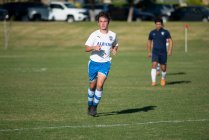 Adolescente futbolista corriendo en el campo durante un juego - foto de stock
