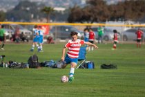 Jugador de fútbol adolescente a punto de golpear la pelota en un tiro libre - foto de stock
