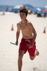 Junior lifegaurd corriendo en la playa - foto de stock