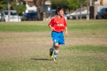 Jeune joueur de soccer faisant du jogging sur le terrain pendant un match — Photo de stock