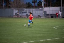 Adolescente futbolista dribleando la pelota durante un juego - foto de stock