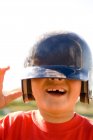 Portrait of young boy missing a tooth with baseball helmet pulled down over his eyes — Stock Photo