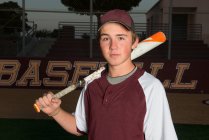 Portrait d'un joueur de baseball du lycée en uniforme marron tenant sa batte — Photo de stock