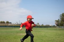 Jovem segurando sua luva e correndo pelo campo de Tball — Fotografia de Stock