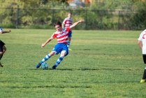 Jugador de fútbol adolescente a punto de golpear la pelota en un tiro libre - foto de stock