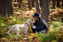Portrait of young tattoed man with his dog in the forest — Stock Photo