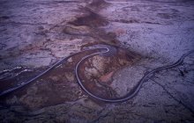 Drone vista di stretta tortuosa strada asfaltata che attraversa terreni rocciosi deserto grezzo in Islanda — Foto stock