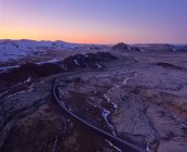 Von oben über der leeren kurvenreichen Autobahn, die durch raues bergiges Gelände in Island bei Sonnenuntergang mit wunderschönem, farbenfrohen Himmel verläuft — Stockfoto