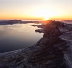 Чудовий ісландський краєвид нерівного скелястого узбережжя з тихою водою і сонцем, що розкинувся над горизонтом. — стокове фото
