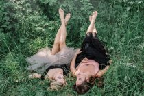 Duas meninas bonitas estão deitadas na grama — Fotografia de Stock