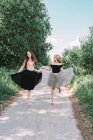 Дві красиві дівчата в повноцінних спідницях танцюють на дорозі — стокове фото