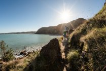 Padre e figlio che camminano su un sentiero di montagna sopra l'oceano in Nuova Zelanda — Foto stock