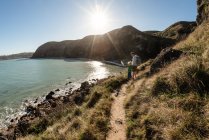 Pai e filho caminhando em um caminho de montanha acima do oceano na Nova Zelândia — Fotografia de Stock