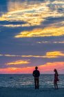 Молодая пара на пляже во время прекрасного летнего заката. — стоковое фото