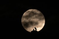Un paio di scalatori che fissano una corda con la luna piena sullo sfondo — Foto stock