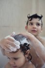 Hermanos bañándose y jugando con espuma - foto de stock