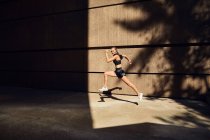 Retrato de bela jovem mulher no elegante sportswear moderno correndo na rua da cidade — Fotografia de Stock