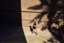 Porträt einer schönen jungen Frau in stylischer moderner Sportbekleidung, die auf der Straße der Stadt posiert — Stockfoto
