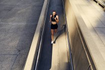 Portrait of beautiful young woman in stylish modern sportswear running on city street — Stock Photo