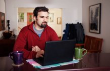 Людина працює на портативному комп'ютері з дому — стокове фото