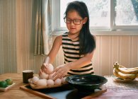 Una chica arregla los huevos en una bandeja de bambú - foto de stock