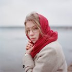 Una mujer está en la orilla del río con una bufanda roja - foto de stock