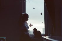 Uma mulher fica na frente de uma janela em um apartamento — Fotografia de Stock