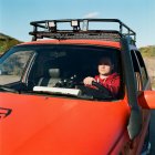 Человек садится за руль автомобиля с картой и биноклем — стоковое фото