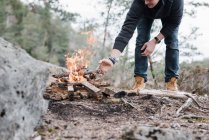 Man putting sticks on a campfire outdoors in Sweden — Stock Photo