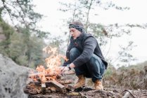 Man putting sticks on a campfire outdoors in Sweden — Stock Photo