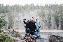 Батько фотографує зі своїми дітьми, насолоджуючись багаттям — стокове фото