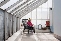Дівчина сидить на стільці в зеленому будинку взимку — стокове фото