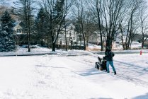 Giovane uomo spazzaneve il suo vialetto dopo una tempesta invernale. — Foto stock