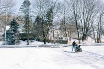 Young man snowplowing his driveway after a winter storm. — Stock Photo