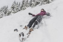 Young woman with hat sliding fast in the snow downhill funny face — Stock Photo