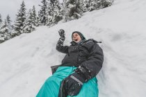Mujer joven con sombrero deslizándose rápido en la nieve cuesta abajo cara divertida - foto de stock