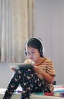 Meninas usam um tablet e ouvem música com fones de ouvido — Fotografia de Stock