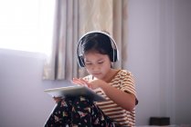 Girls use a tablet and listen to music with headphones — Stock Photo