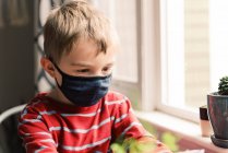 Cute boy wearing face mask at home — Stock Photo