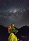 Junger Mann sitzt auf einem Felsen im Anden-Gebirge mit der milchigen — Stockfoto