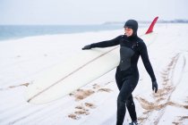 Young woman going surfing in winter snow — Stock Photo
