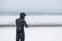 Чоловік готується до серфінгу під час зимового снігу — стокове фото