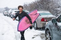 Чоловік готується до серфінгу під час зимового снігу — стокове фото