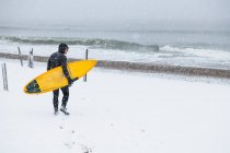 Hombre practicando surf durante la nieve invernal - foto de stock