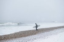 Homem que vai surfar durante a neve de inverno — Fotografia de Stock