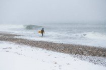 Чоловік збирається серфінг під час зимового снігу — стокове фото
